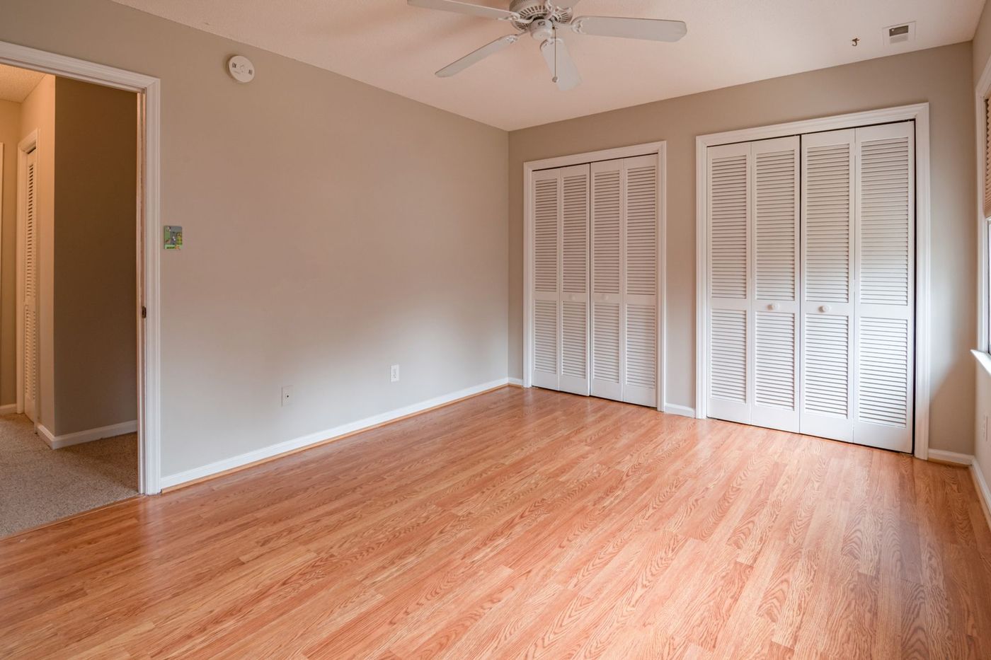 An empty room with polished wooden flooring and built-in wardrobes, cleared after a move